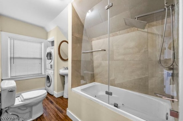 bathroom with toilet, stacked washer / drying machine, lofted ceiling, wood-type flooring, and shower / bath combination with glass door