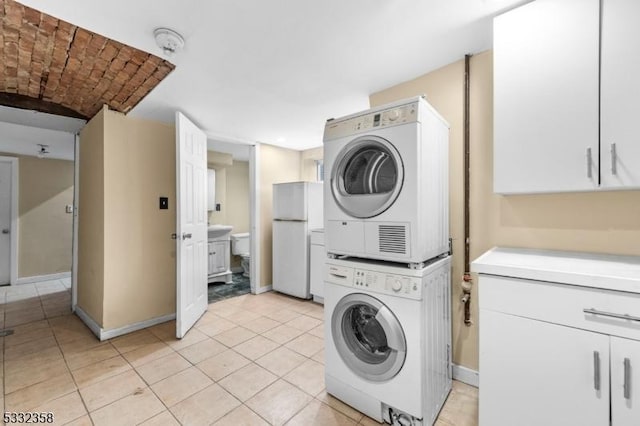 laundry area with stacked washer and dryer, brick ceiling, and light tile patterned floors