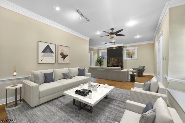 living room featuring ceiling fan, hardwood / wood-style flooring, track lighting, and ornamental molding