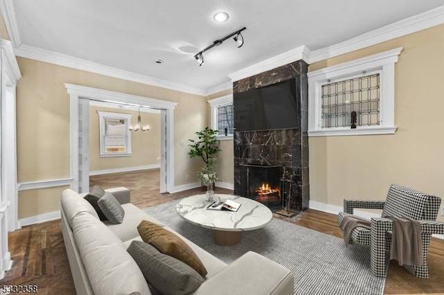 sitting room with a high end fireplace, rail lighting, ornamental molding, and hardwood / wood-style floors