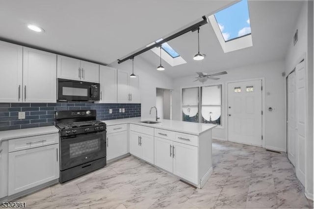 kitchen with kitchen peninsula, vaulted ceiling with skylight, black appliances, white cabinetry, and ceiling fan