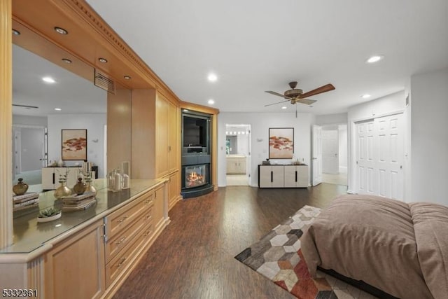 bedroom featuring ceiling fan, a closet, dark hardwood / wood-style flooring, and connected bathroom