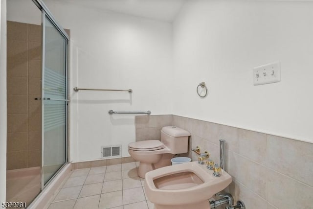 bathroom with a bidet, tile walls, a shower with shower door, toilet, and tile patterned floors