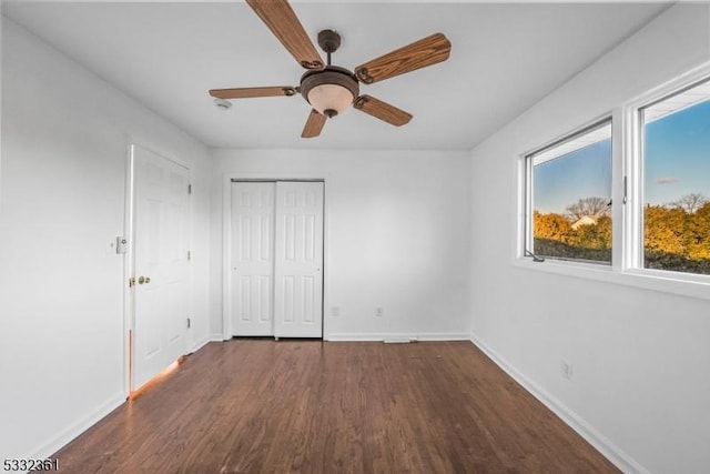 unfurnished bedroom featuring dark wood-type flooring, ceiling fan, and a closet