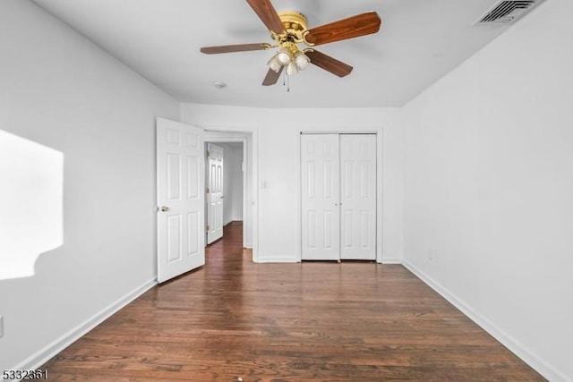 unfurnished bedroom with ceiling fan, dark wood-type flooring, and a closet