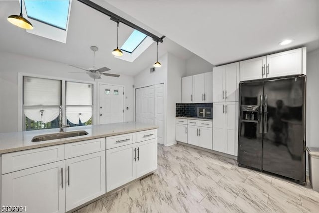 kitchen featuring lofted ceiling with skylight, white cabinets, black fridge with ice dispenser, backsplash, and sink