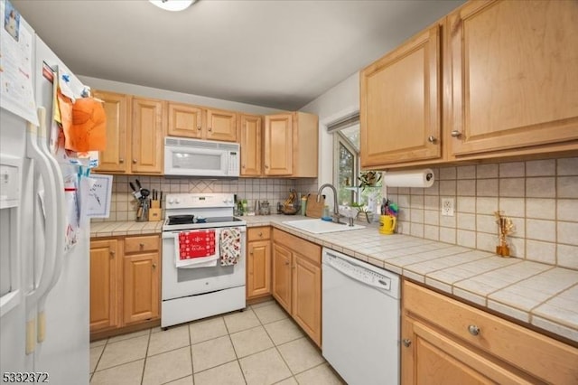 kitchen featuring sink, white appliances, light tile patterned flooring, and tile countertops