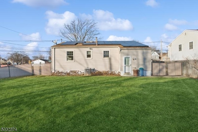 back of property with a lawn and solar panels