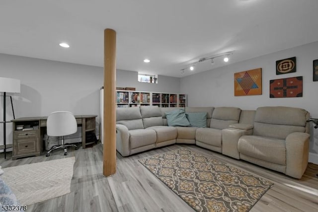 living room with baseboard heating, track lighting, and light wood-type flooring