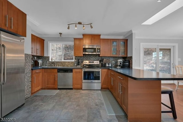 kitchen featuring stainless steel appliances, a skylight, kitchen peninsula, a kitchen bar, and tasteful backsplash