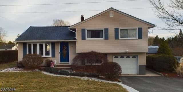 tri-level home with a garage and a front lawn