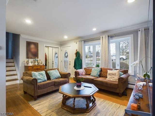 living room featuring baseboard heating, crown molding, and light hardwood / wood-style flooring