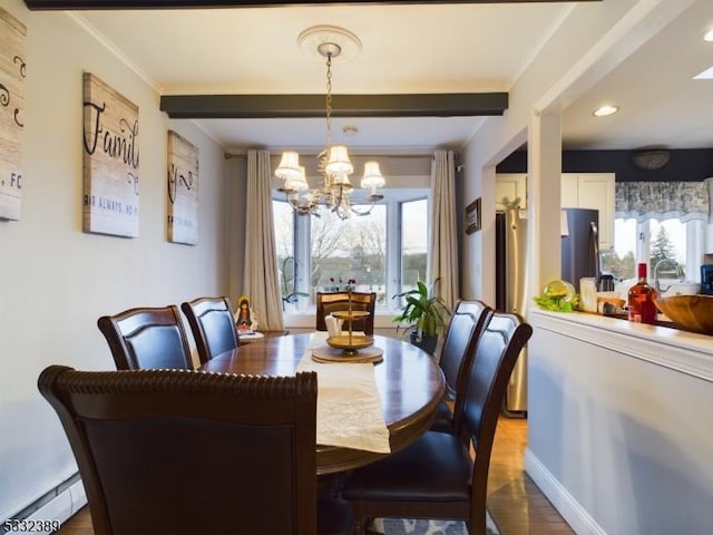 dining space with a healthy amount of sunlight, a chandelier, a baseboard radiator, and ornamental molding