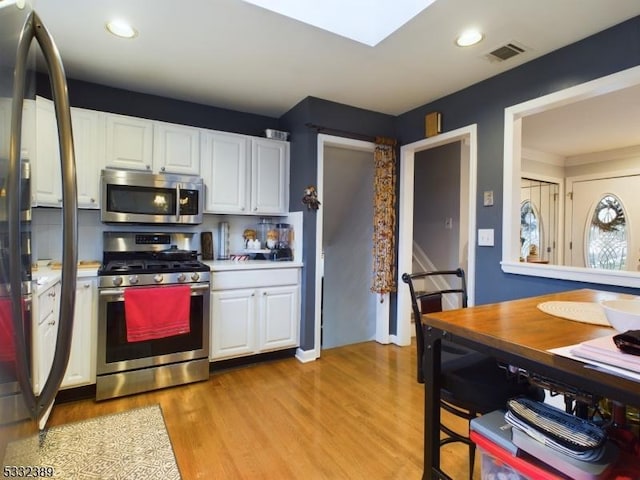 kitchen featuring appliances with stainless steel finishes, light hardwood / wood-style floors, and white cabinetry