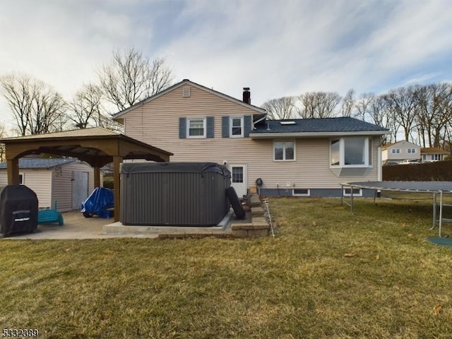 rear view of property featuring a trampoline, a hot tub, a storage shed, and a lawn