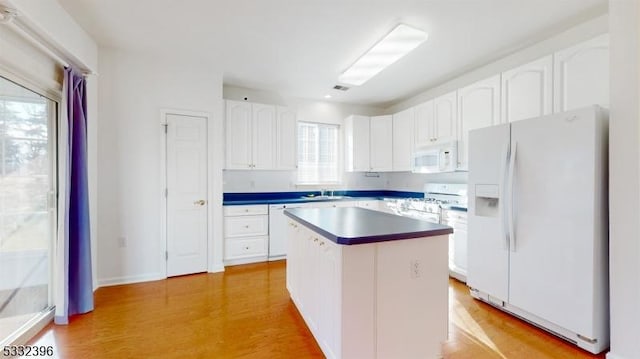 kitchen with white appliances, a center island, light hardwood / wood-style floors, white cabinets, and sink