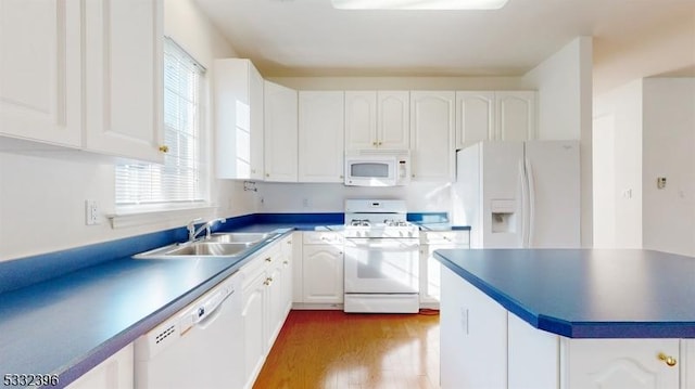 kitchen featuring white appliances, white cabinets, wood-type flooring, and sink