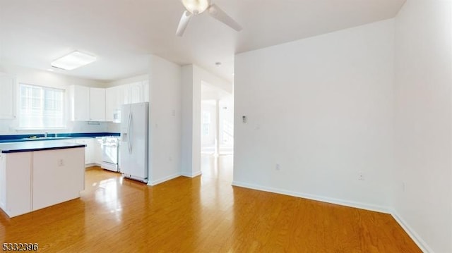 kitchen with range, white cabinets, light wood-type flooring, and white fridge with ice dispenser