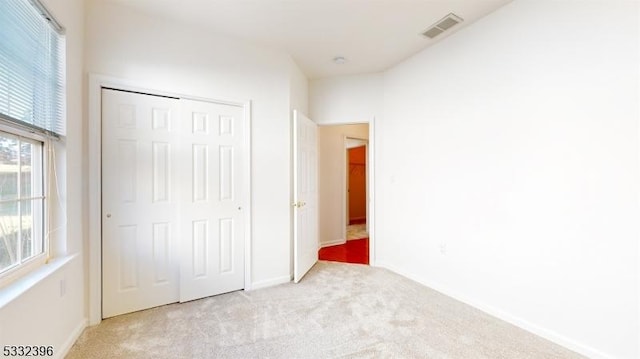 unfurnished bedroom featuring light colored carpet and a closet