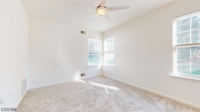 empty room featuring ceiling fan, light carpet, and plenty of natural light