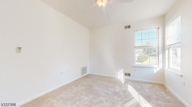 empty room with ceiling fan, plenty of natural light, and light colored carpet