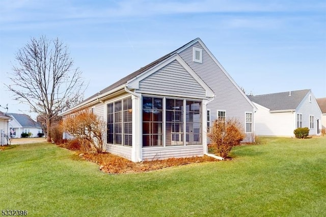 back of property with a lawn and a sunroom