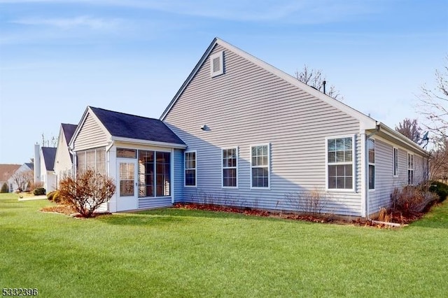 rear view of house featuring a lawn and a sunroom