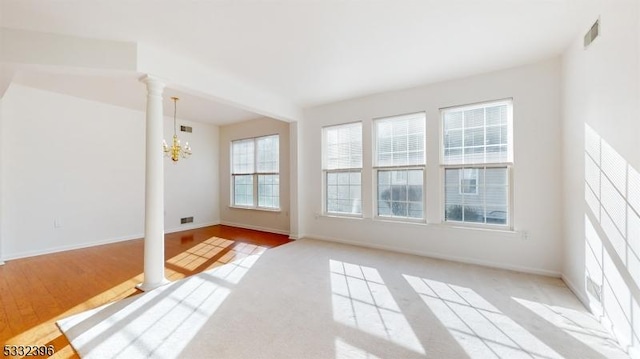 unfurnished room featuring a notable chandelier and ornate columns