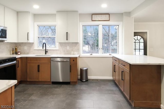 kitchen with sink, white cabinets, kitchen peninsula, and appliances with stainless steel finishes