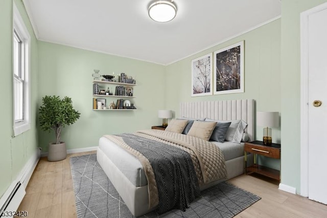 bedroom with a baseboard heating unit and light hardwood / wood-style flooring