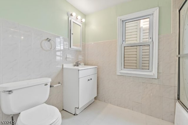 full bathroom featuring tile patterned flooring, shower / bath combination with glass door, tile walls, toilet, and vanity