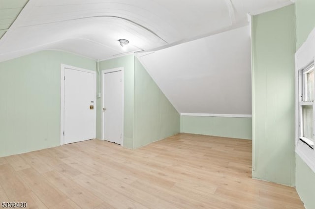 bonus room featuring light wood-type flooring and vaulted ceiling