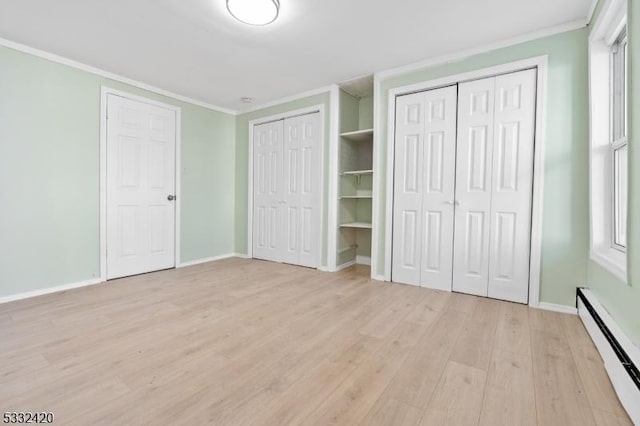 unfurnished bedroom with a baseboard radiator, two closets, multiple windows, and light hardwood / wood-style flooring