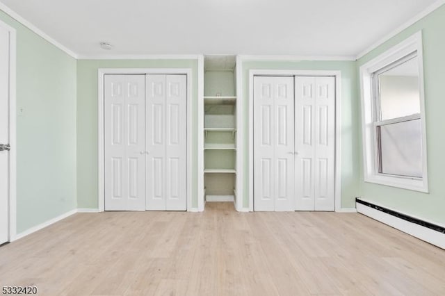 unfurnished bedroom with a baseboard heating unit, light wood-type flooring, two closets, and ornamental molding