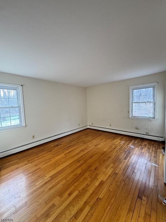 unfurnished room featuring a wealth of natural light, light hardwood / wood-style floors, and a baseboard heating unit