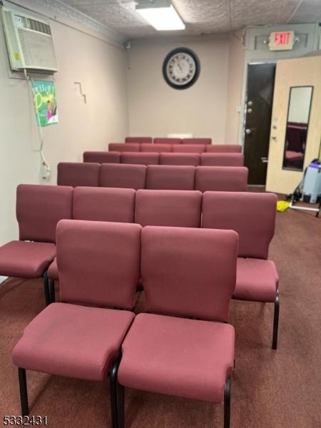 carpeted home theater room with ornamental molding and an AC wall unit