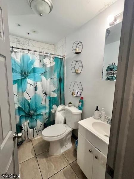 bathroom with toilet, vanity, tile patterned flooring, and curtained shower