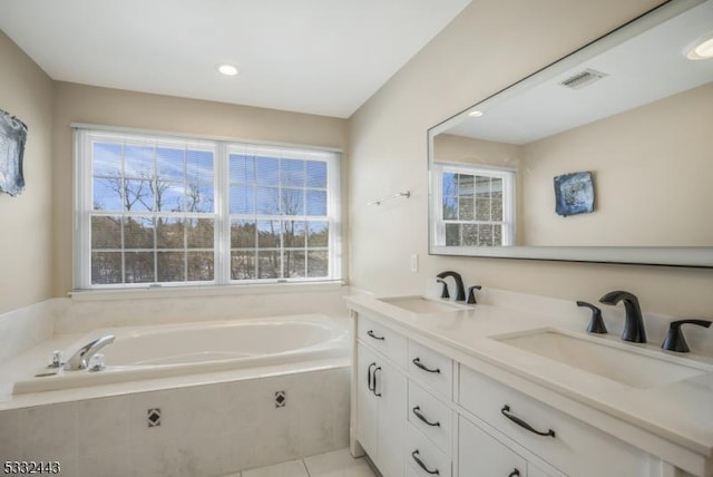 bathroom featuring tile patterned flooring, a relaxing tiled tub, and vanity