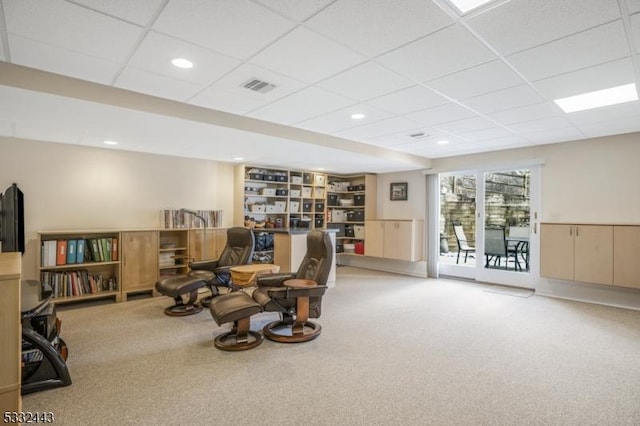 living area with carpet flooring and a drop ceiling