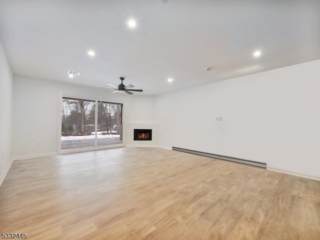 unfurnished living room featuring ceiling fan, light hardwood / wood-style floors, and a baseboard heating unit