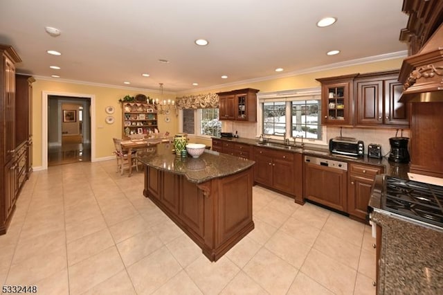 kitchen with gas stove, sink, crown molding, decorative backsplash, and a kitchen island