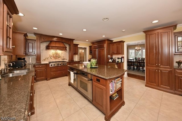 kitchen featuring a center island, premium range hood, decorative backsplash, appliances with stainless steel finishes, and a chandelier