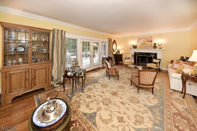 living room with a fireplace, french doors, ornamental molding, and light hardwood / wood-style flooring