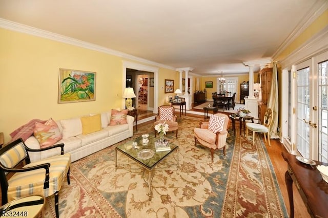 living room featuring ornate columns, hardwood / wood-style floors, french doors, and ornamental molding