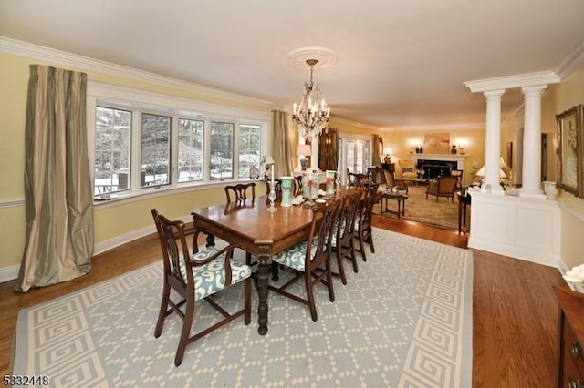 dining space with hardwood / wood-style flooring, ornate columns, ornamental molding, and a notable chandelier