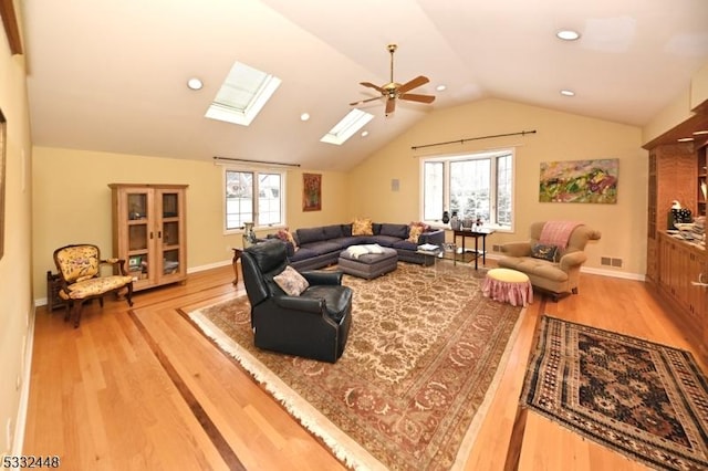 living room with hardwood / wood-style flooring, ceiling fan, and lofted ceiling with skylight