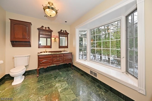 bathroom featuring vanity, toilet, and a healthy amount of sunlight