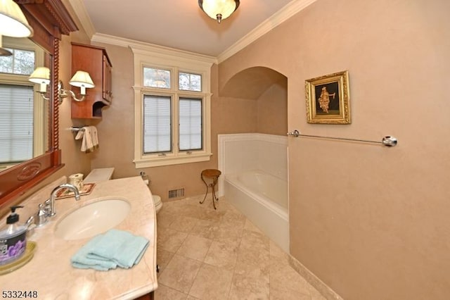 bathroom featuring vanity, a tub to relax in, toilet, and ornamental molding