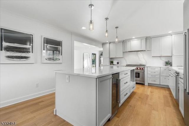 kitchen with stainless steel stove, light hardwood / wood-style flooring, decorative backsplash, decorative light fixtures, and a kitchen island