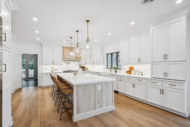 kitchen featuring decorative light fixtures, a center island, a kitchen bar, and white cabinetry